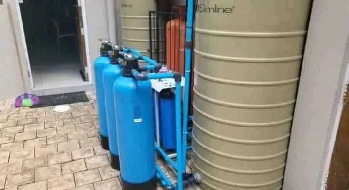 Water tank connected to blue filtration vessels and pipework